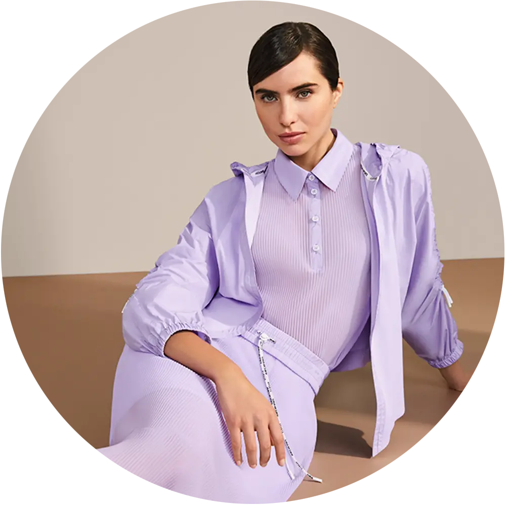 Marc Cain Pastels Woman in a pastel blouse and shirt seated.