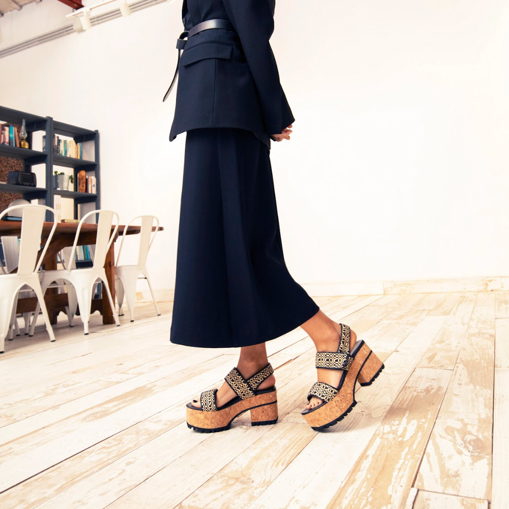 Homers-navy-sandal Woman in a navy dress wearing Homers high heel cork sandals, standing by a table on hardwood floors.