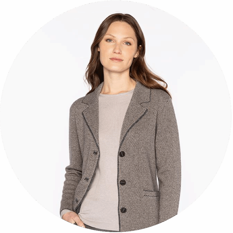 A woman wears a flannel cashmere herringbone jacket over a neutral sweater